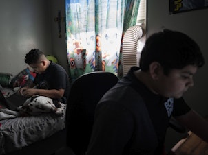 caption: Eloyd, 11, left, plays online video games with his brother Emmanuel, 12, right, at his home in Uvalde, Texas.