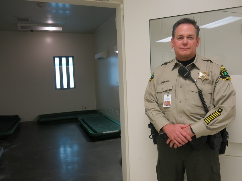 caption: Maj. Scott Robertson with the Snohomish County Sheriff's Office displays an empty room in the jail's medical unit. Access to buprenorphine means fewer inmates are housed here with opioid withdrawal symptoms. 