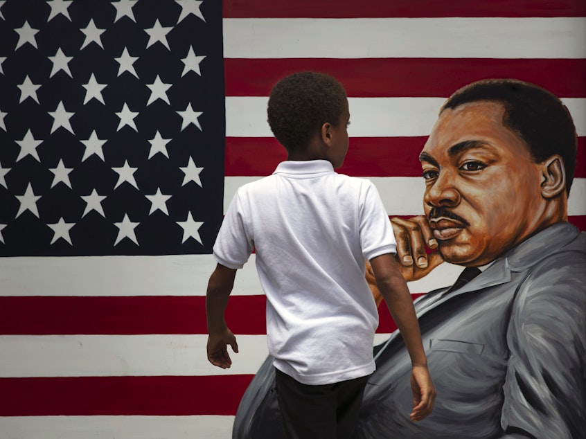 caption: A young boy walks past a painting depicting Dr. Martin Luther King Jr. during a Juneteenth celebration in Los Angeles in 2020. Juneteenth marks the day in 1865 when federal troops arrived in Galveston, Texas, to take control of the state and ensure all enslaved people be freed, more than two years after the Emancipation Proclamation.