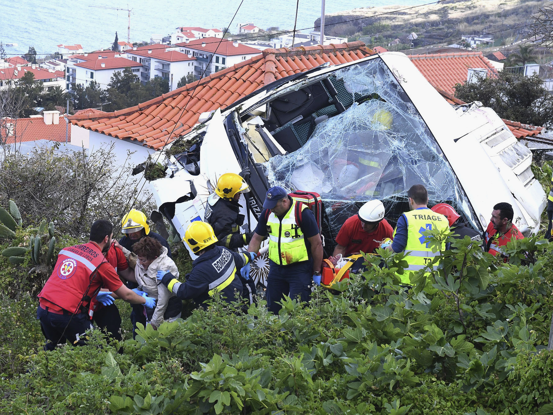 caption: Rescue workers help a person who was inside a tour bus that crashed Wednesday in Caniço, a coastal town on Portugal's island of Madeira.