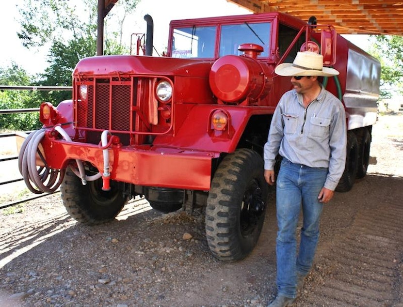 caption: A water tender for fighting wildfires is parked next to rancher Charlie Lyon’s barn near Mountain Home, Idaho.