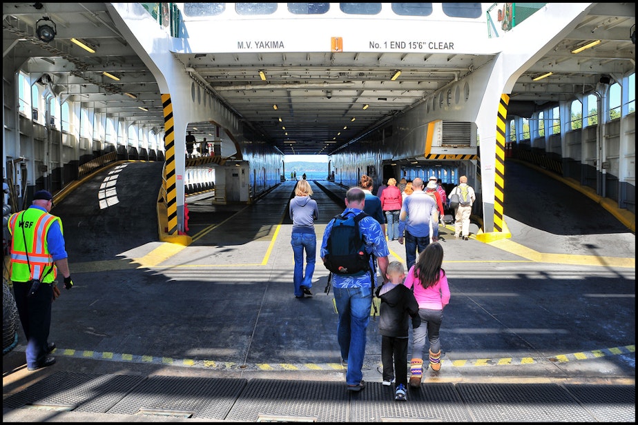 caption: Walk-on passengers board a Washington State Ferry. Passengers who walk on to the ferry can skip the long wait lines for people who are driving on. 