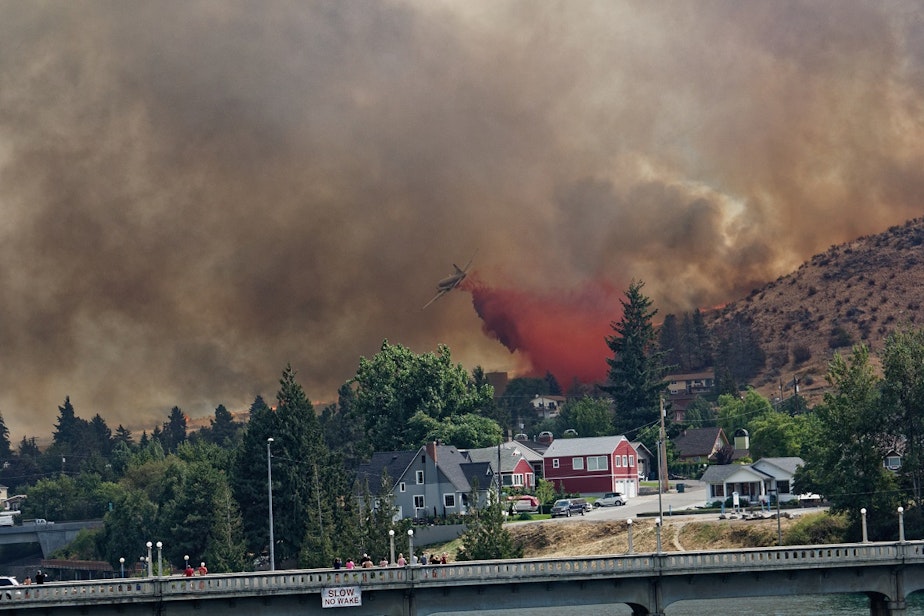 caption: A plane dumps fire retardant on a ballooning wildfire on Aug. 14, 2015.