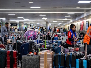 caption: Airline staff search through unclaimed luggage at the William P. Hobby Airport on Wednesday in Houston.