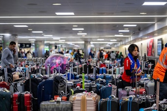 caption: Airline staff search through unclaimed luggage at the William P. Hobby Airport on Wednesday in Houston.
