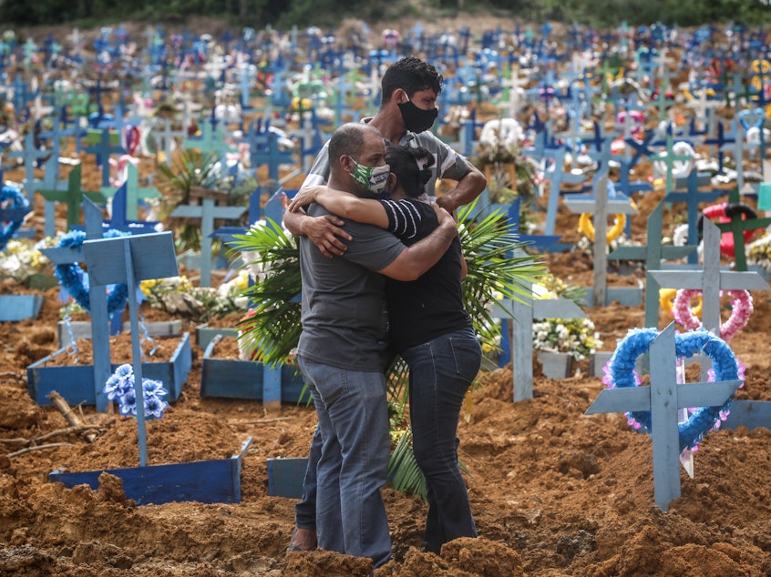 caption: Relatives at a mass burial of pandemic victims at the Parque Taruma cemetery in Manaus, Brazil, mourn a family member.