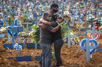 caption: Relatives at a mass burial of pandemic victims at the Parque Taruma cemetery in Manaus, Brazil, mourn a family member.
