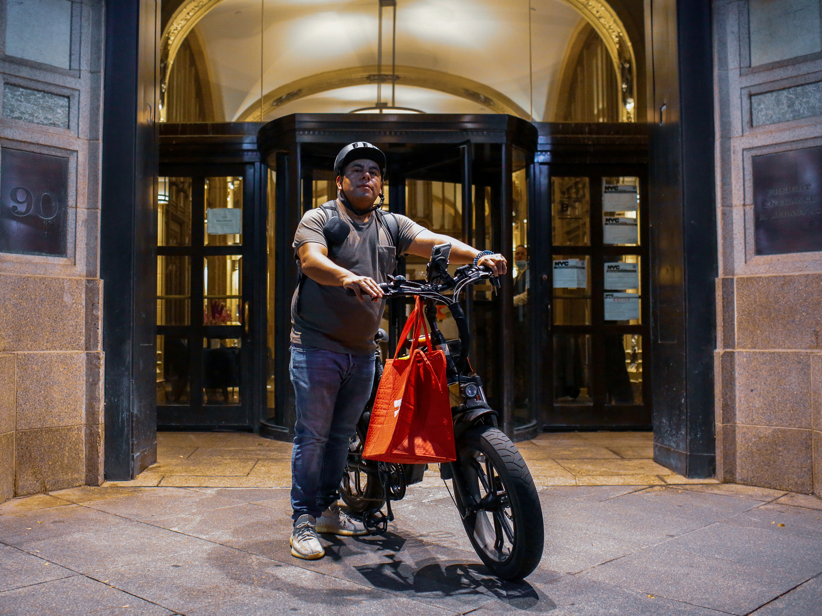 caption: Gustavo Ajche delivers food for DoorDash in Lower Manhattan. Ajche, who has helped organized 3,000 other food delivery workers during the pandemic, was one of the activists who helped get legislation passed to improve working conditions and pay for the couriers, October 15, 2021.