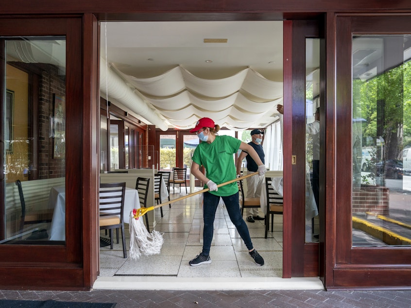 caption: A cafe employee in Washington, D.C., cleans in preparation for reopening.