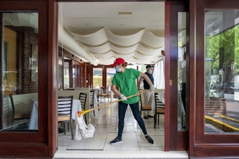 caption: A cafe employee in Washington, D.C., cleans in preparation for reopening.