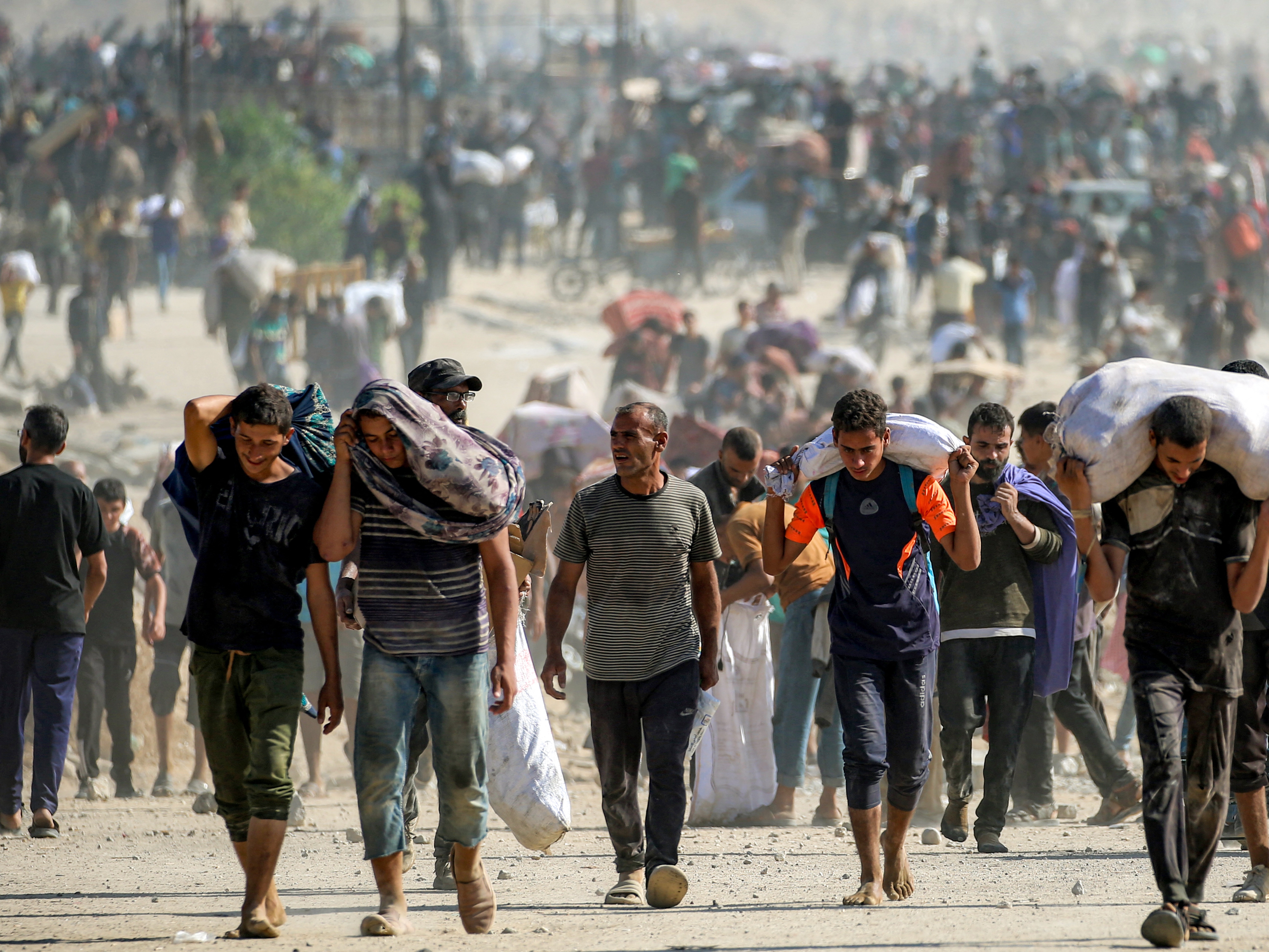 caption: People walk with humanitarian aid packages that they received from a distribution center in Nuseirat in the central Gaza Strip, on Tuesday.