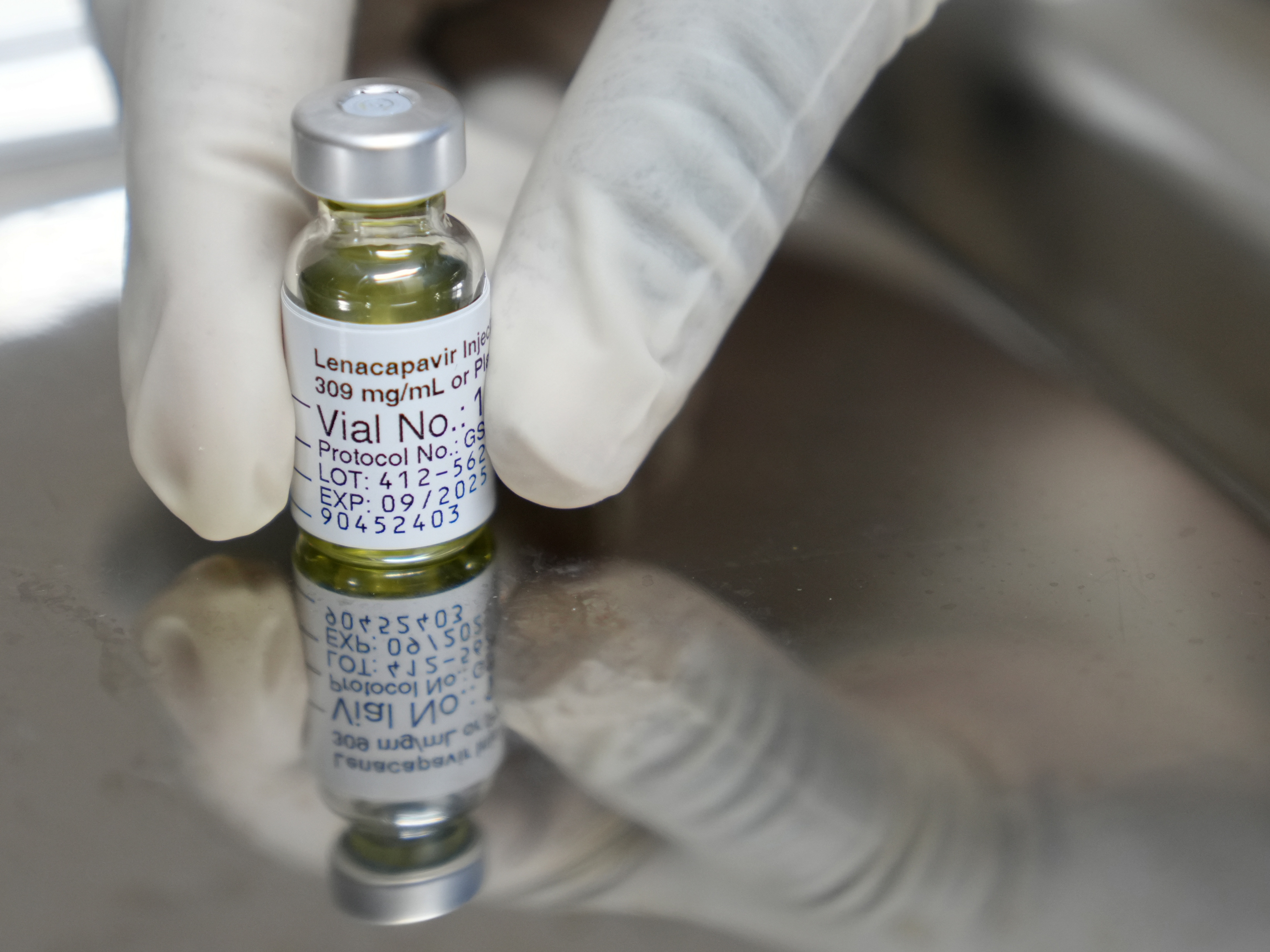 caption: A pharmacist holds a vial of lenacapavir, the HIV prevention injectable drug that was shown to be 100% effective in newly published clinical trial data.