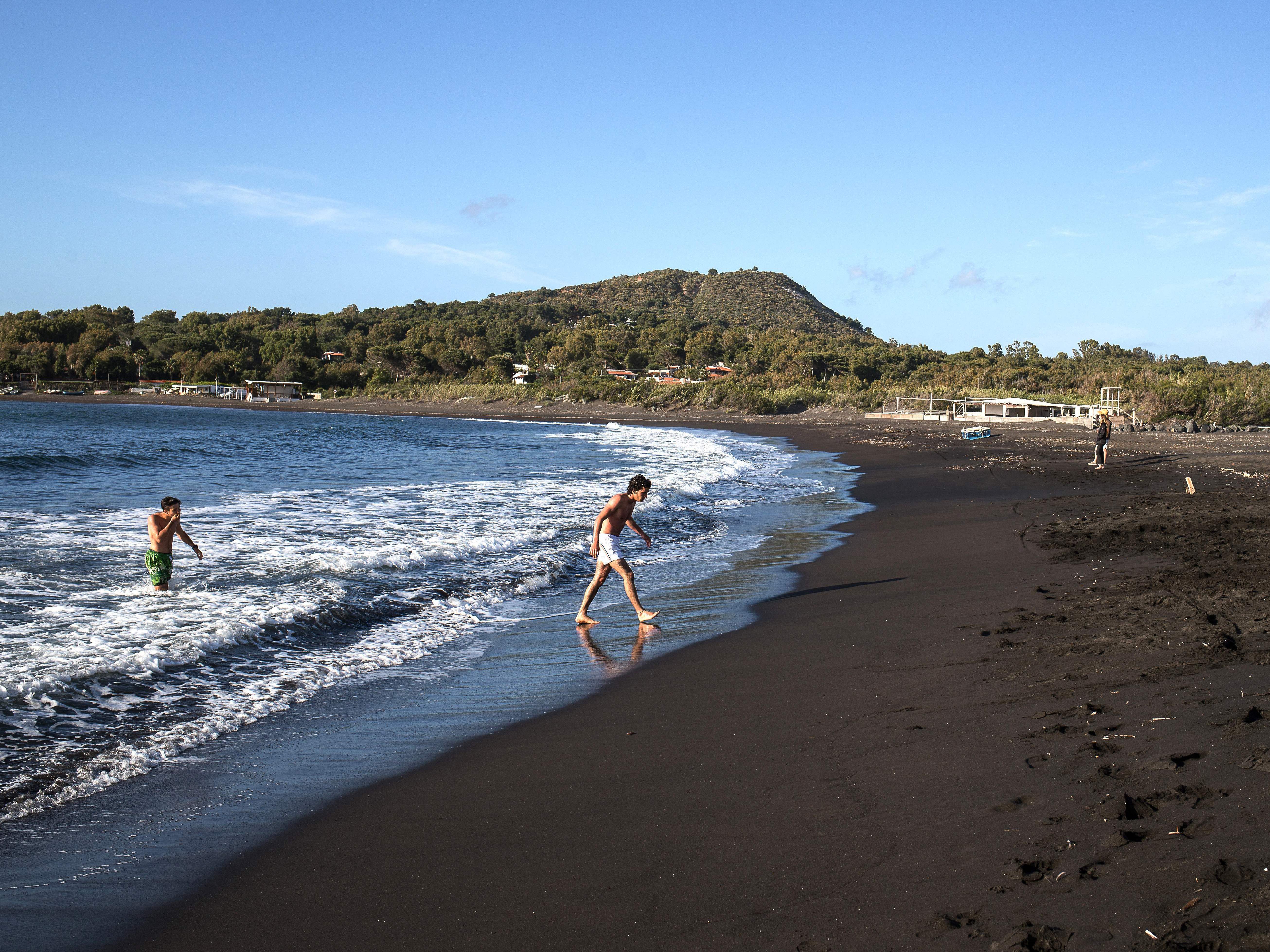 caption: The European Union is poised to open travel to more visitors after ambassadors approved changes to travel restrictions Wednesday. Here, people walk out of the sea last week on Italy's volcanic island of Vulcano.