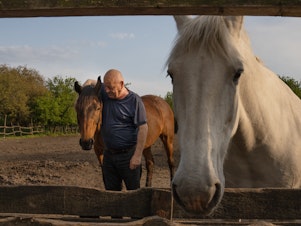 caption: Yuriy Kopishynskyi stands with a horse at his family's horseback riding school on Khortytsia, an island on the Dnipro River just outside Zaporizhzhia, Ukraine.