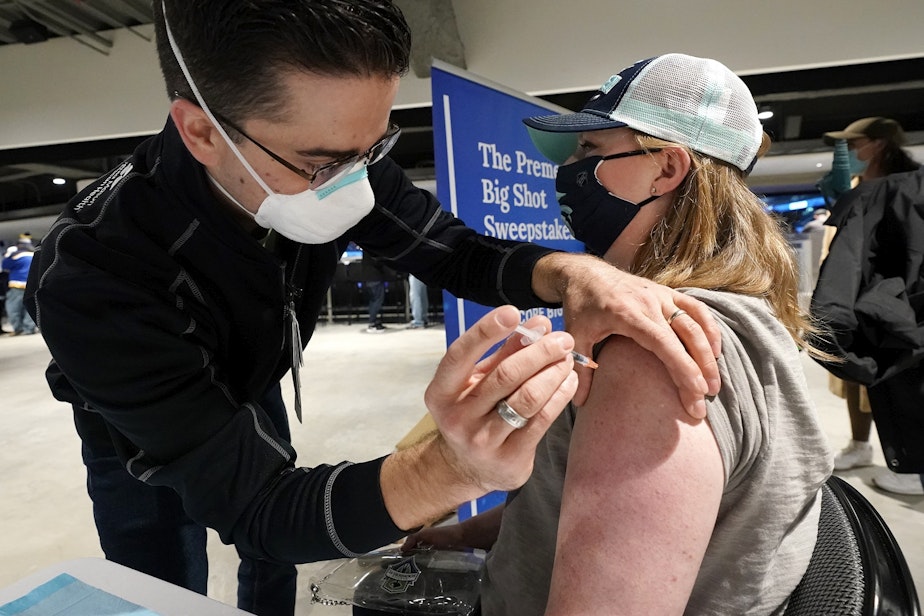 caption: Seattle Kraken fan Jami Lopez, right, of Bellevue, Wash., receives a Moderna coronavirus booster vaccine from health care worker Zach Hren at the arena before the Kraken's NHL hockey game against the St. Louis Blues, Friday, Jan. 21, 2022, in Seattle. The boosters were available to fans at the pop-up clinic at the Thursday and Friday Kraken games.