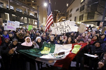 caption: People cheer during a rally to oppose President Donald Trump's executive order barring people from certain Muslim nations from entering the United States, Sunday, Jan. 29, 2017, in downtown Seattle. 