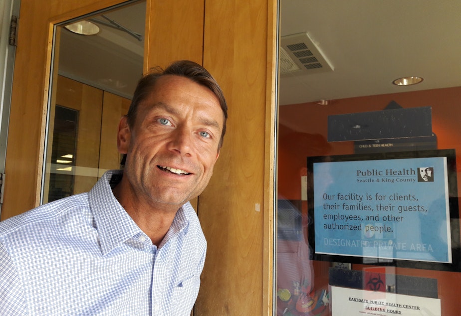 TJ Cosgrove stands next to a new sign that greets patients entering Public Seattle-King County's Eastgate clinic.