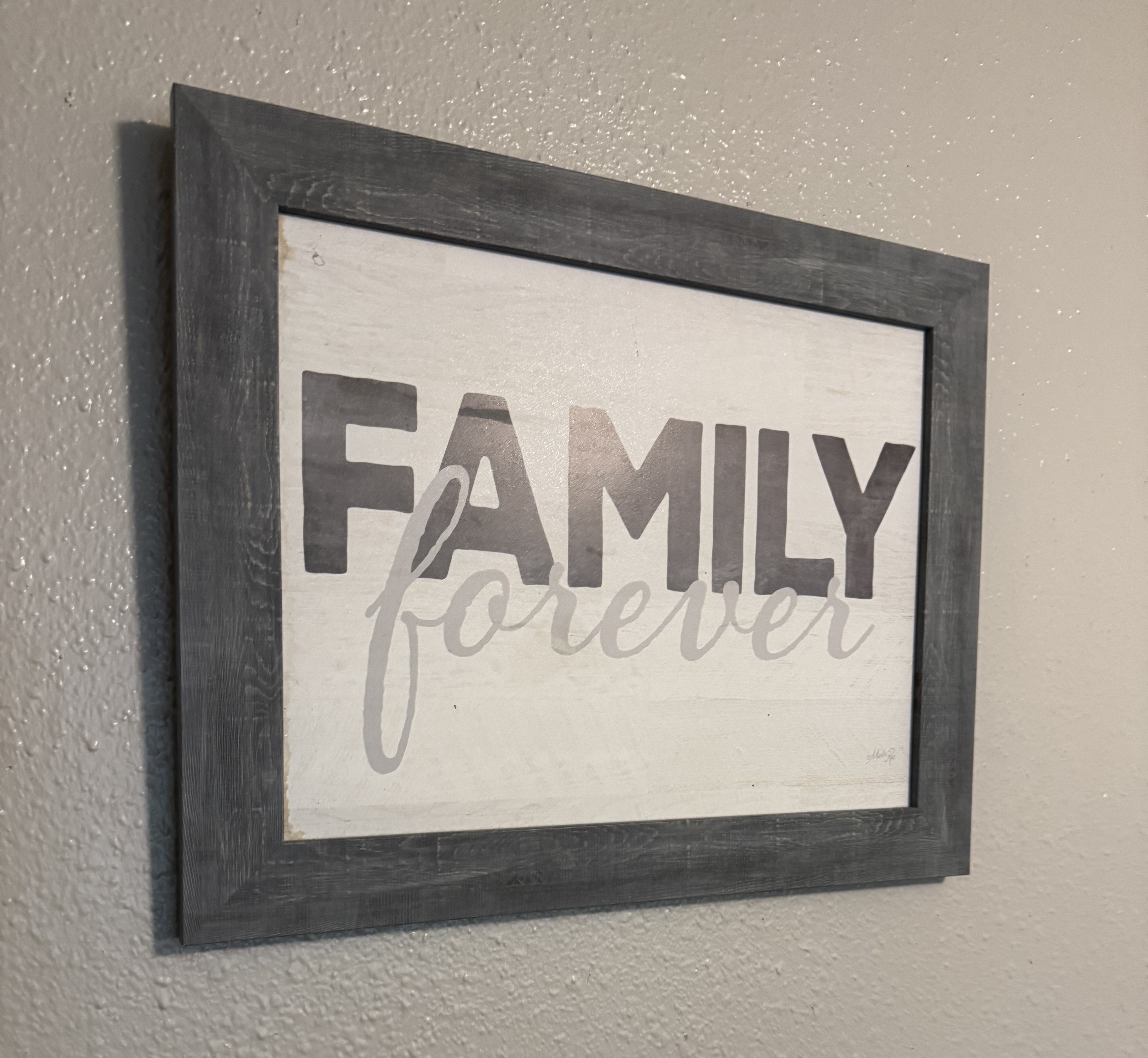 caption: A picture frame hanging above the dining table at Espinoza's home in Kent, WA.