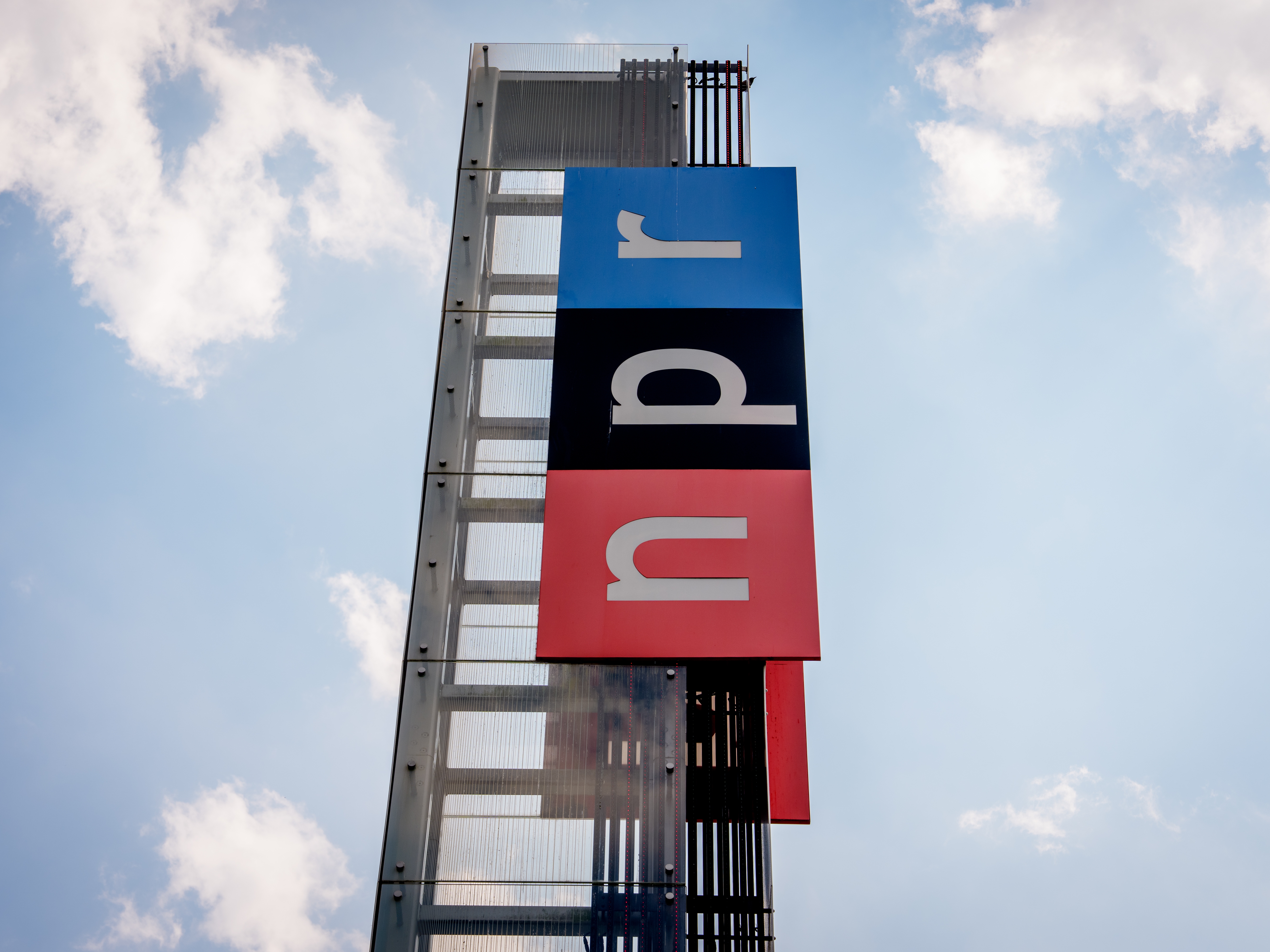 caption: View of the sign outside National Public Radio headquarters on July 22, 2025 in Washington, DC.