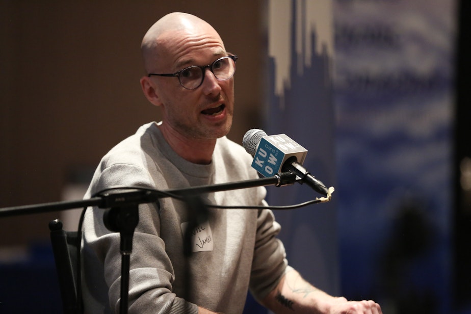 caption: Will James, host of the "Lost Patients" podcast, talks about the show during a live event at the Seattle's Central Library on May 9, 2024.