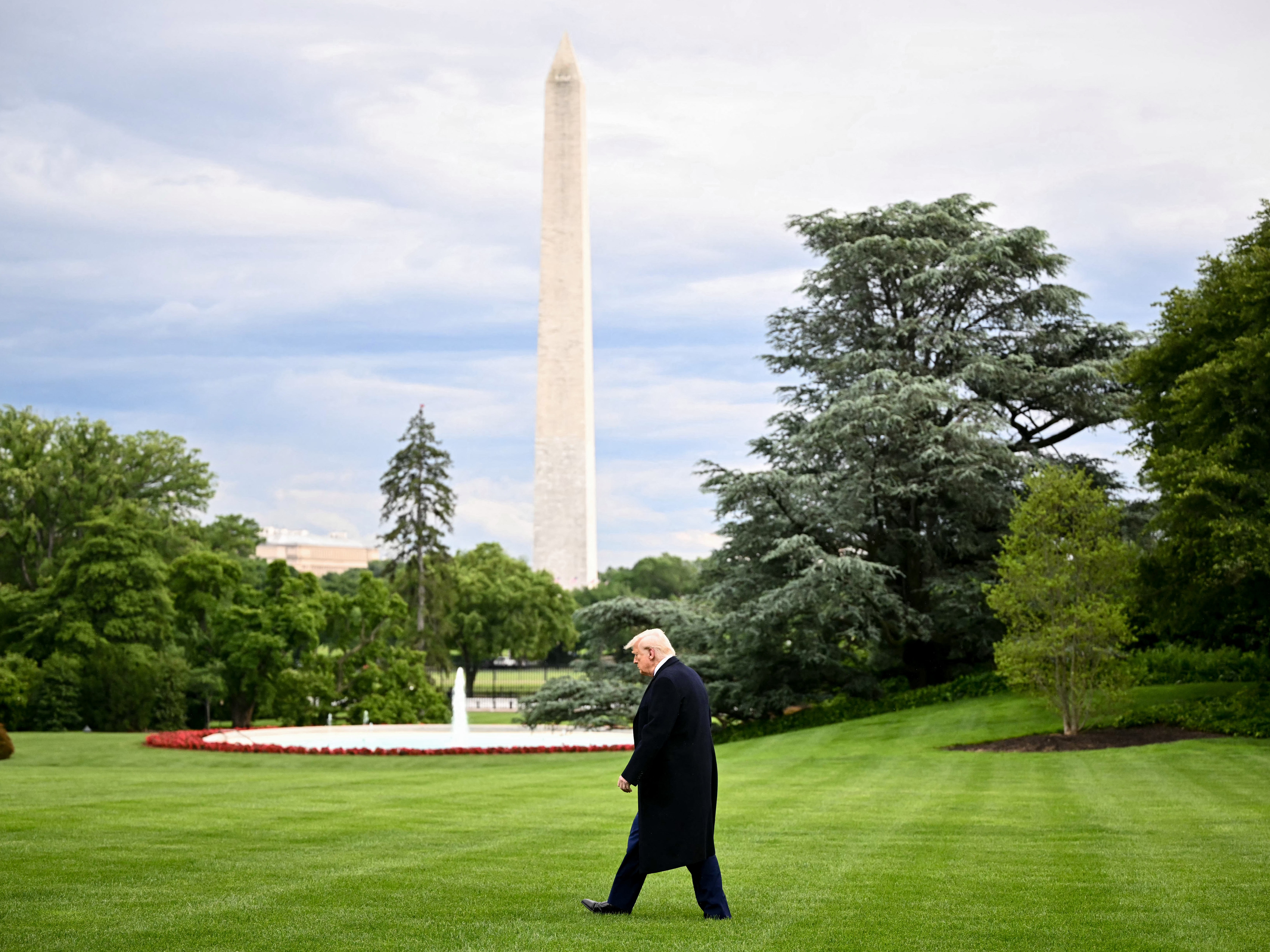 caption: President Donald Trump is pictured walking to Marine One to depart the White House in May, with the Washington Monument in the background.