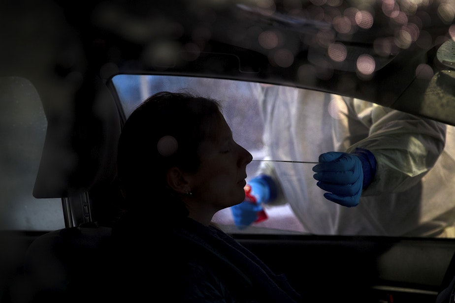 caption: Mark Radford, a paramedic with King County Medic One, administers a Covid-19 test on Wednesday, November 18, 2020, in the parking lot of the Weyerhaeuser King County Aquatic Center along Southwest Campus Drive in Federal Way. 