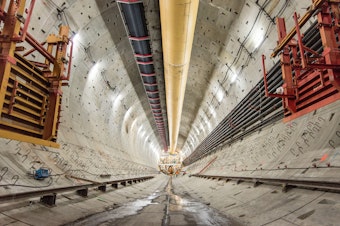 caption: A view to the back end of Bertha, the SR 99 tunneling machine. The steel hooks on both sides of the wall of the tunnel will become part of the foundation that will support the decks and walls of the future roadway, according to the state.