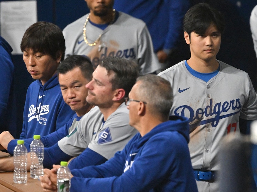 caption: Baseball star Shohei Ohtani (right) and his interpreter, Ippei Mizuhara (left), are seen in the dugout in the 2024 MLB Seoul Series game between the Los Angeles Dodgers and the San Diego Padres. The Dodgers have fired Mizuhara after Ohtani's representatives claimed he was the victim of "a massive theft."