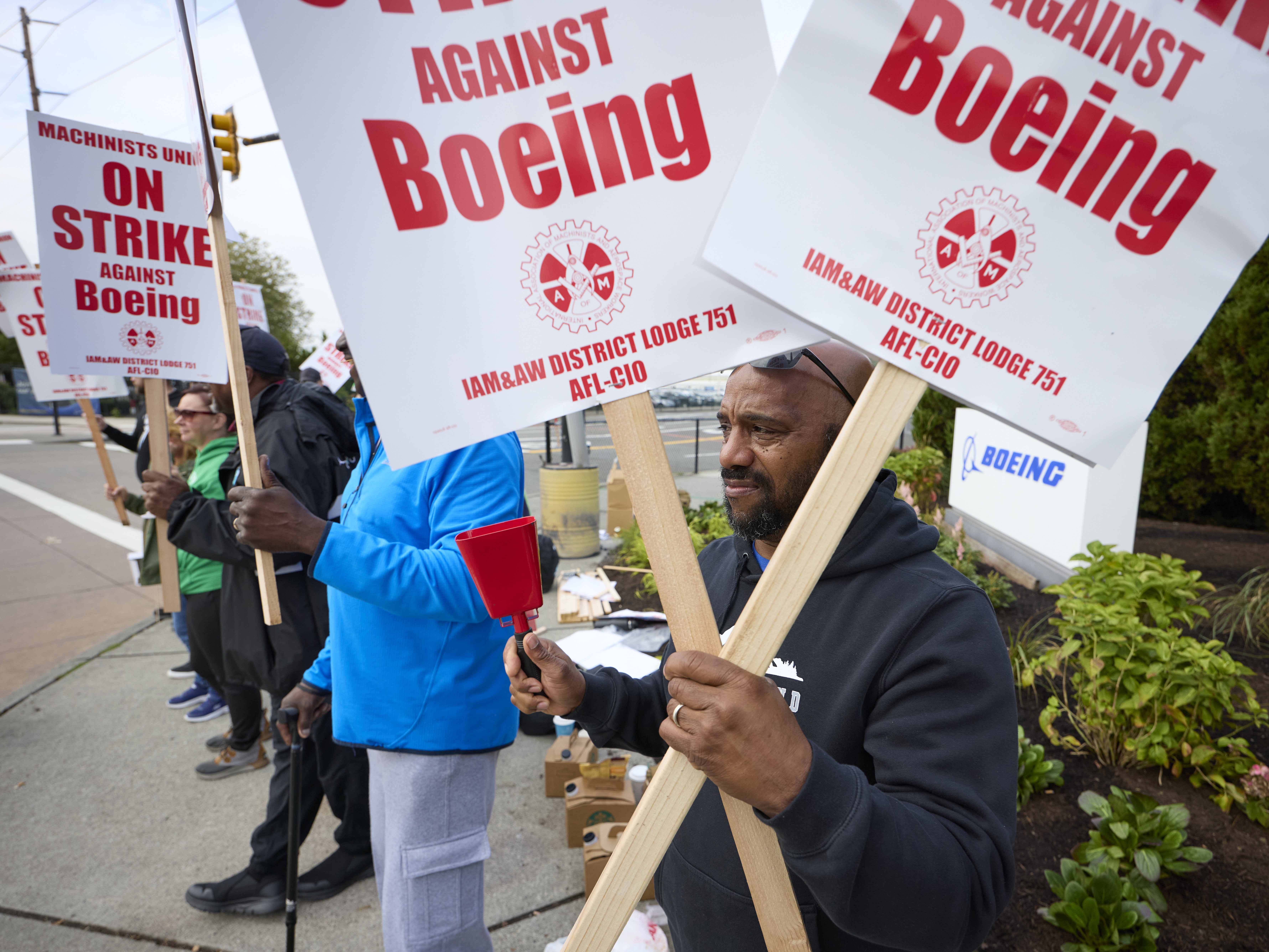 caption: Boeing workers hold signs on the picket line at the Renton assembly plant on Friday in Renton, Washington.