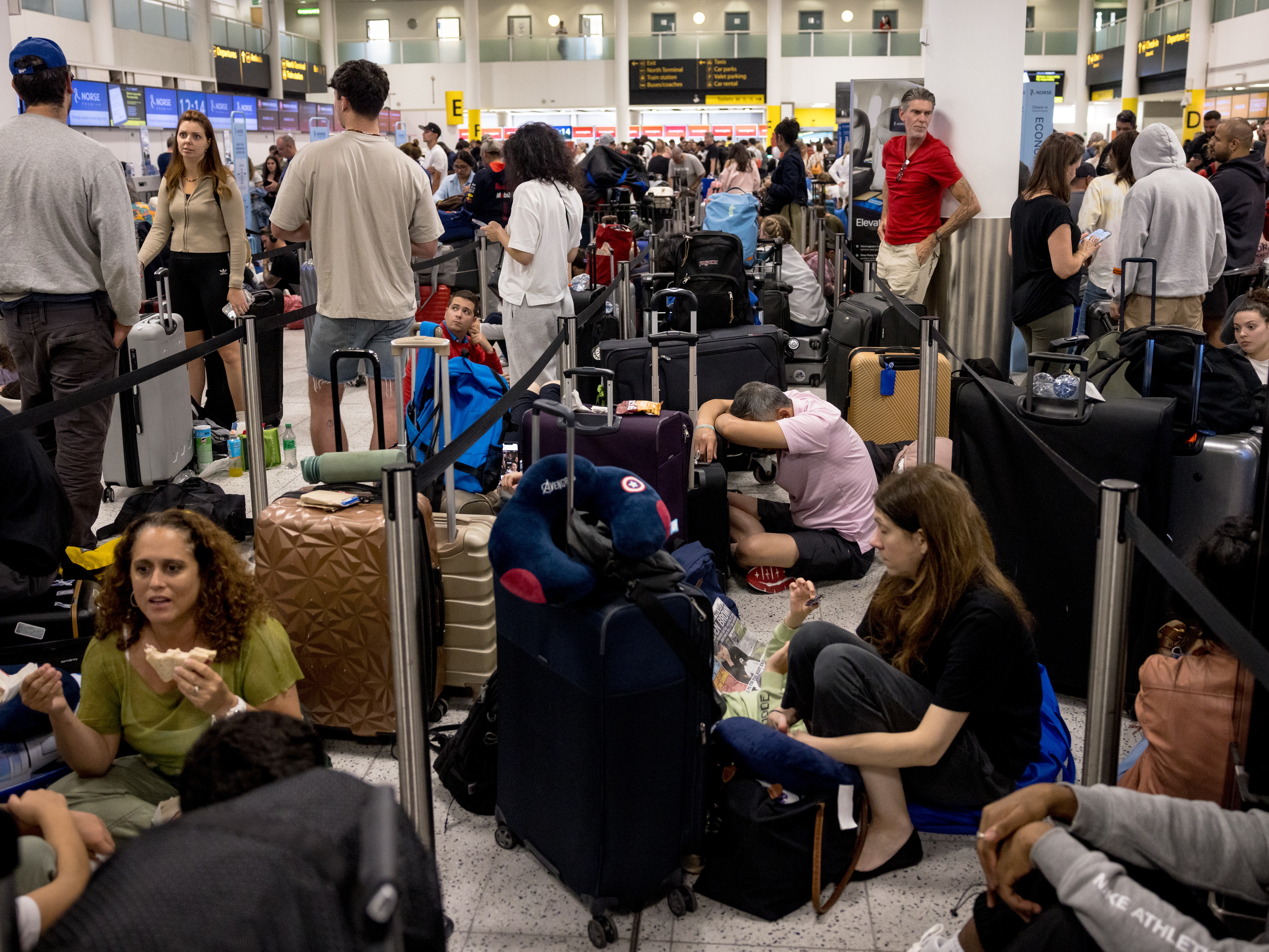 caption: Passengers line up at London's Gatwick Airport amid a global IT outage on Friday.  