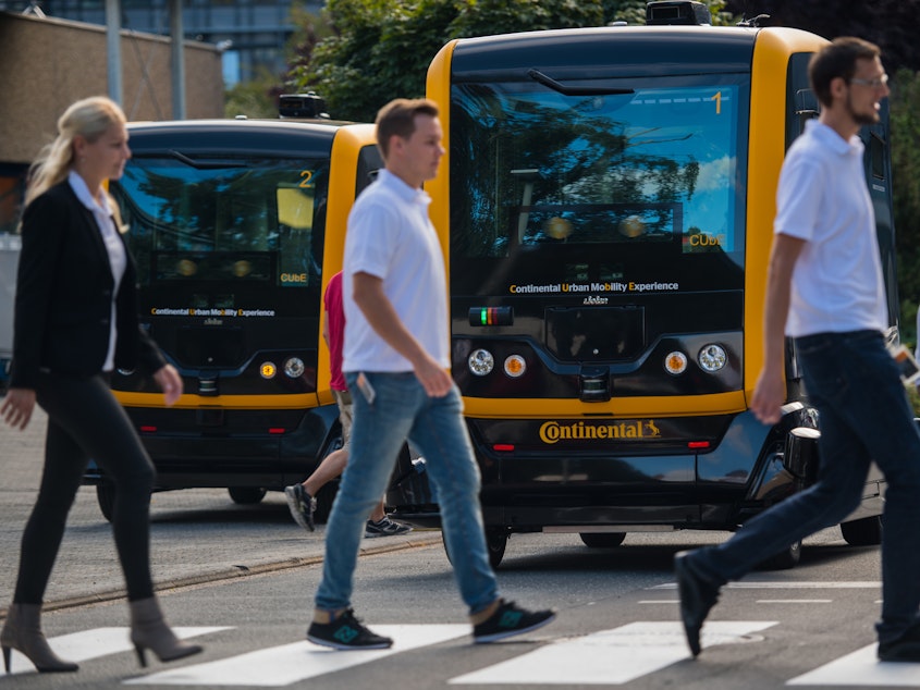 caption: New research explores how people think autonomous vehicles should handle moral dilemmas. Here, people walk in front of an autonomous taxi being demonstrated in Frankfurt, Germany, last year.