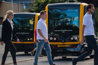 caption: New research explores how people think autonomous vehicles should handle moral dilemmas. Here, people walk in front of an autonomous taxi being demonstrated in Frankfurt, Germany, last year.