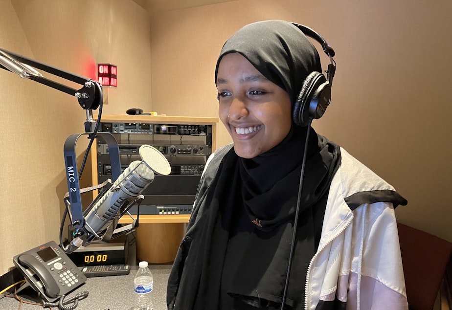 caption: Najuma Abadir records narration for her RadioActive story at KUOW on May 7, 2022. 