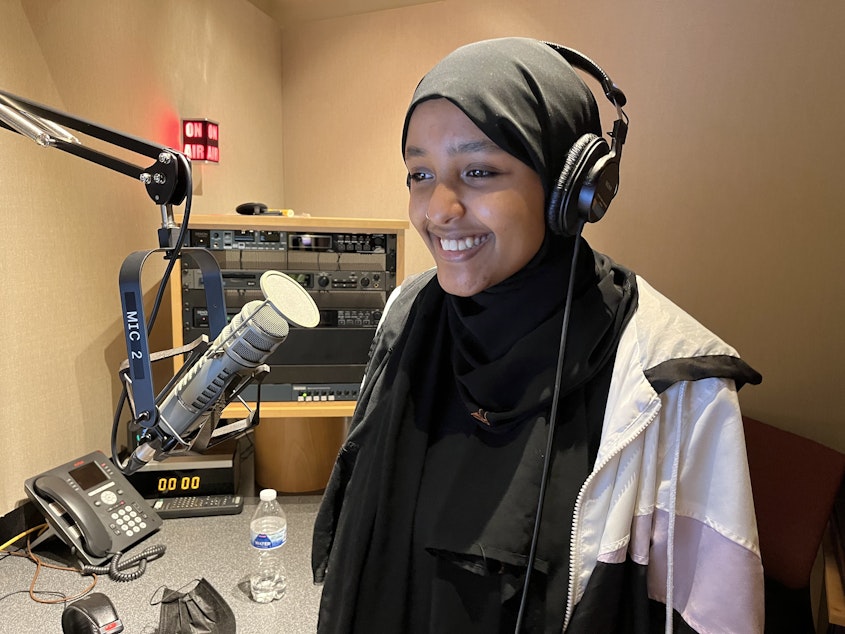 caption: Najuma Abadir records narration for her RadioActive story at KUOW on May 7, 2022. 