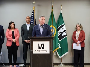caption: King County Executive Dow Constantine stands with members of the County Council and public health community at a press conference on Monday, March 4, 2024.