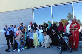 caption: Omar Ali with his family. Omar is standing fourth form the left holding his daughter.
