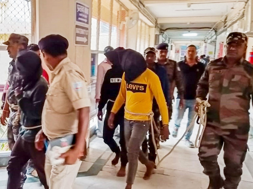 caption: Police escort men accused of allegedly raping a tourist to a district court in Dumka, in India's Jharkhand state, on March 4. The attack took place on March 1; the woman posted a video describing what happened on social media.
