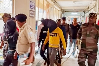 caption: Police escort men accused of allegedly raping a tourist to a district court in Dumka, in India's Jharkhand state, on March 4. The attack took place on March 1; the woman posted a video describing what happened on social media.