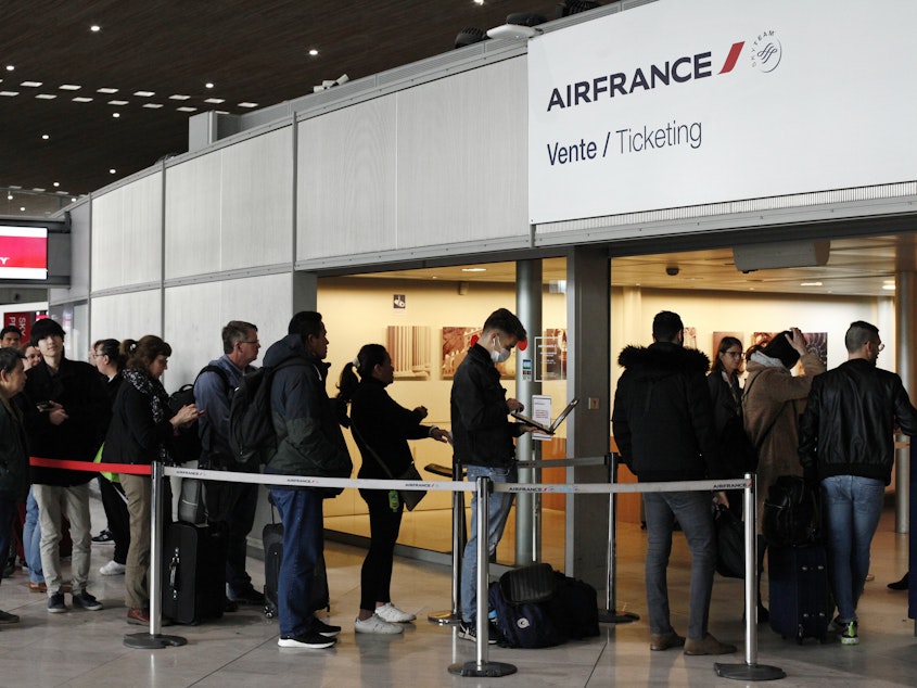 caption: Passengers wait in front of the Air France desk at an airport near Paris on Thursday, a day after President Trump announced a 30-day ban on travel from most of Europe to the United States.