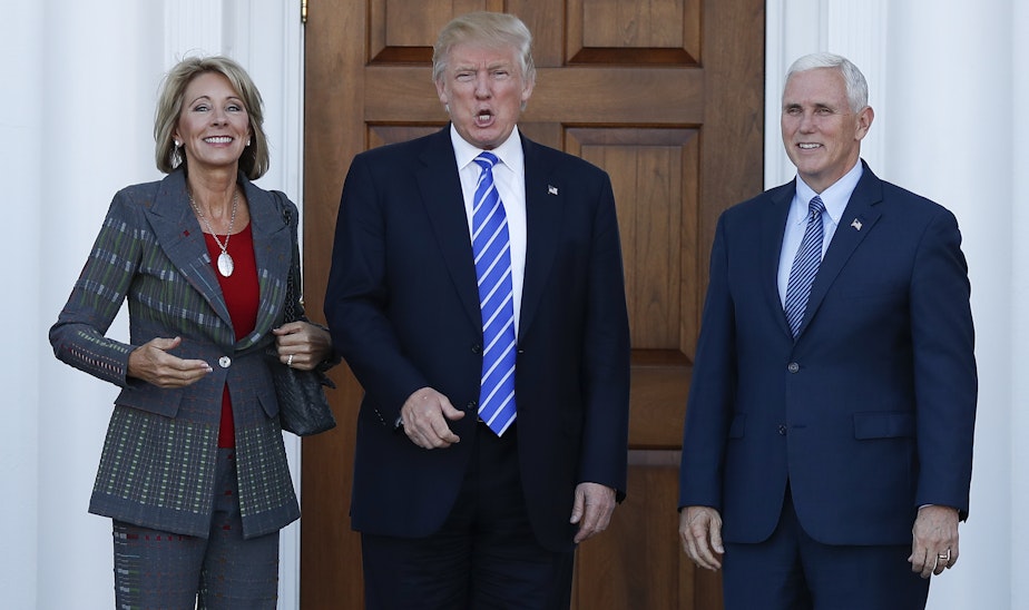 caption: President-elect Donald Trump calls out to media as he Vice President-elect Mike Pence and Betsy DeVos pose for photographs at Trump National Golf Club Bedminster clubhouse in Bedminster, N.J., Saturday, Nov. 19, 2016.