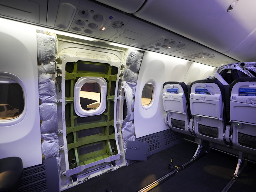 caption: The door plug area of an Alaska Airlines Boeing 737 Max 9 aircraft, seen with the paneling removed, awaits inspection Wednesday at the airline's facilities at Seattle-Tacoma International Airport in SeaTac, Washington.