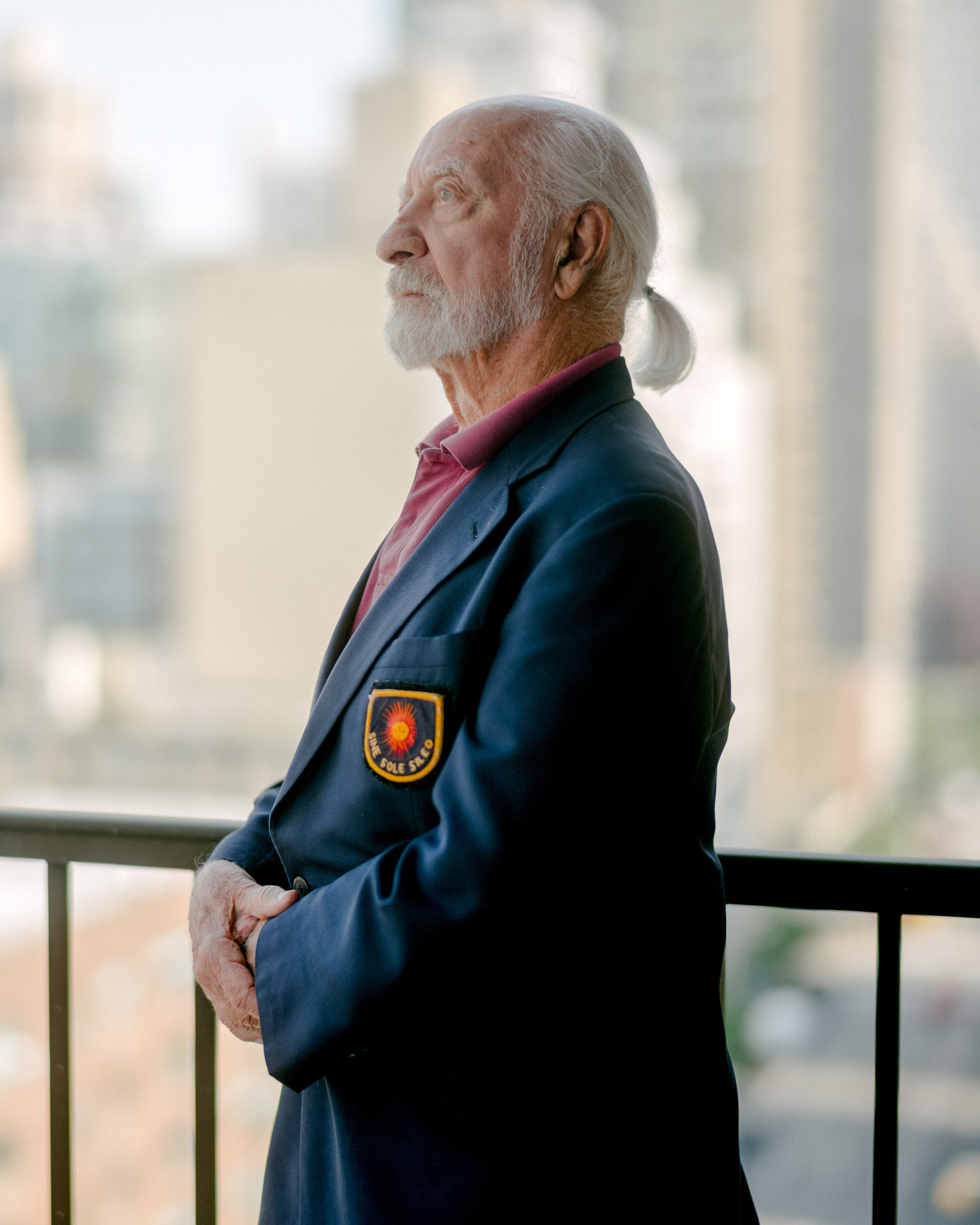 caption: Elliot Berman, on the balcony of his New York City apartment, wears a boat jacket that he and his team donned for meetings with the boating industry about their solar panels. On the pocket is a drawing of a sundial and the Latin phrase <em>Sine sole sileo </em>—<em> </em>"Without sun, I'm silent."