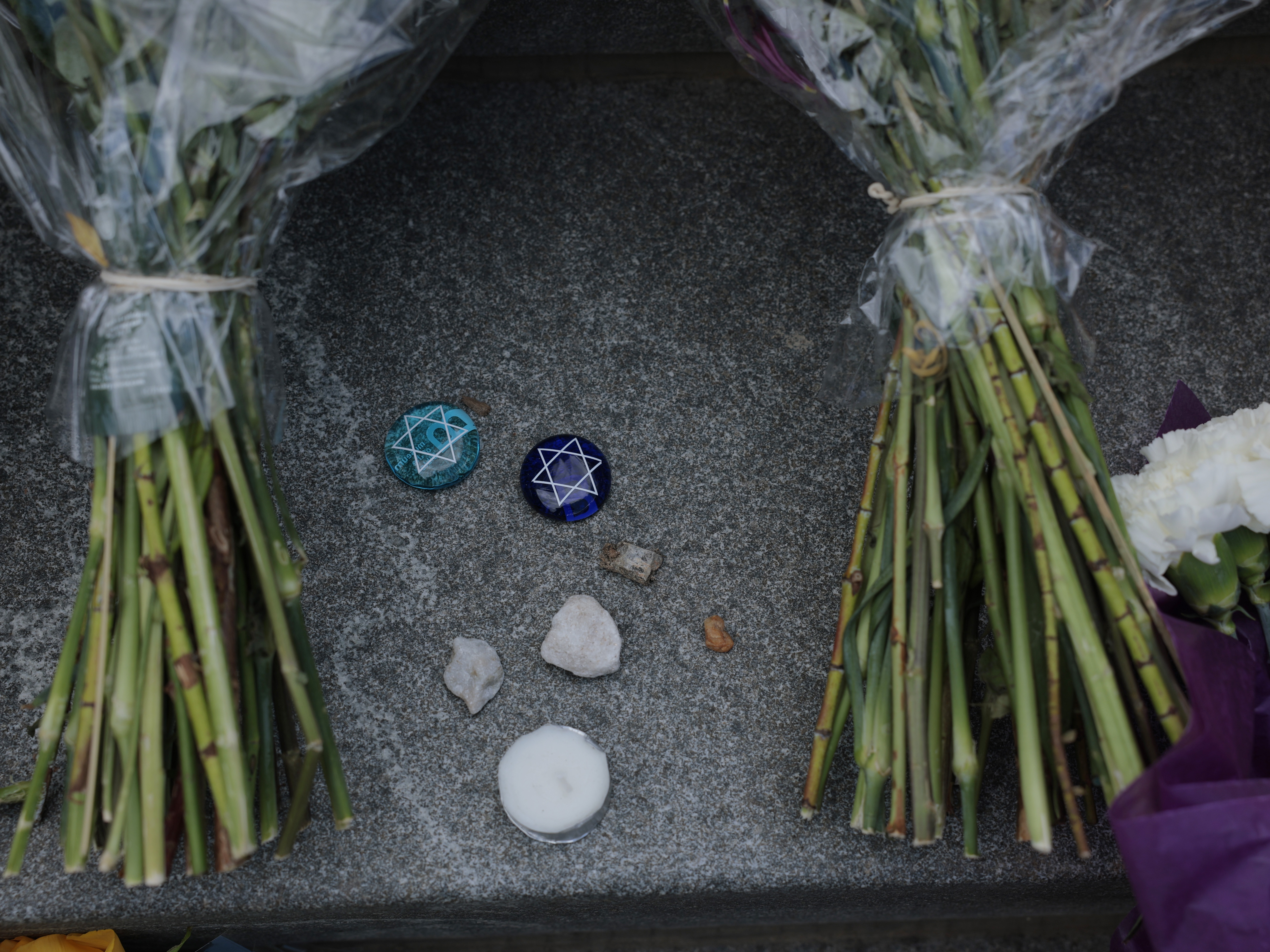 caption: Flowers and stones are left outside the Lillian and Albert Small Capital Jewish Museum on May 23 in Washington, D.C.