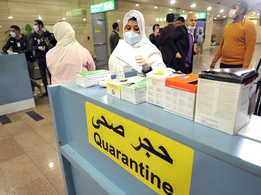 caption: Employees of the Egyptian Quarantine Authority prepare to scan the body temperature of incoming travelers at Cairo International Airport.