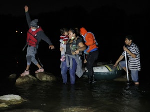 caption: A group of migrants from El Salvador arrives in Roma, Texas, after crossing the Rio Grande on March 30, 2021 in Roma, Texas.
