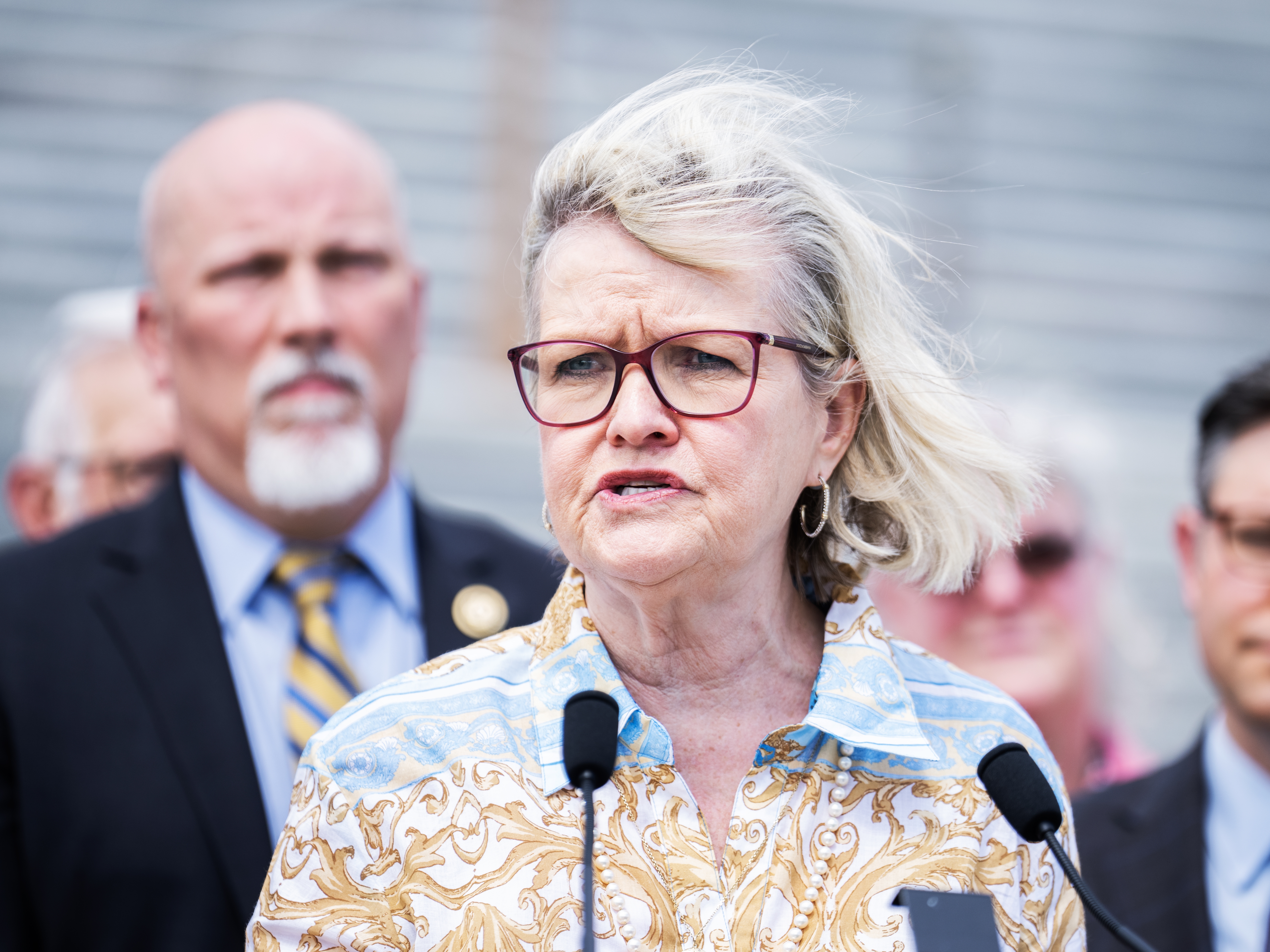 caption: Cleta Mitchell, head of the Election Integrity Network, speaks during a May 2024 news conference outside the U.S. Capitol to introduce the Safeguard American Voter Eligibility (SAVE) Act, which would require proof of U.S. citizenship to register to vote in federal elections. The bill is sponsored by Rep. Chip Roy, R-Texas, who's at left.