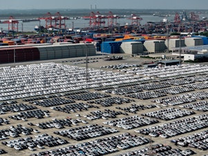 caption: China is aiming to become a global automotive powerhouse, particularly when it comes to electric vehicles. Here, cars wait to be loaded onto a ship at a port in Nanjing.