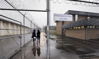 caption: FILE: In this photo taken Thursday, Jan. 28, 2016, staff members head past razor wire-topped fences and into a building hosting a University Behind Bars program at the Monroe Correctional Complex in Monroe, Wash. 