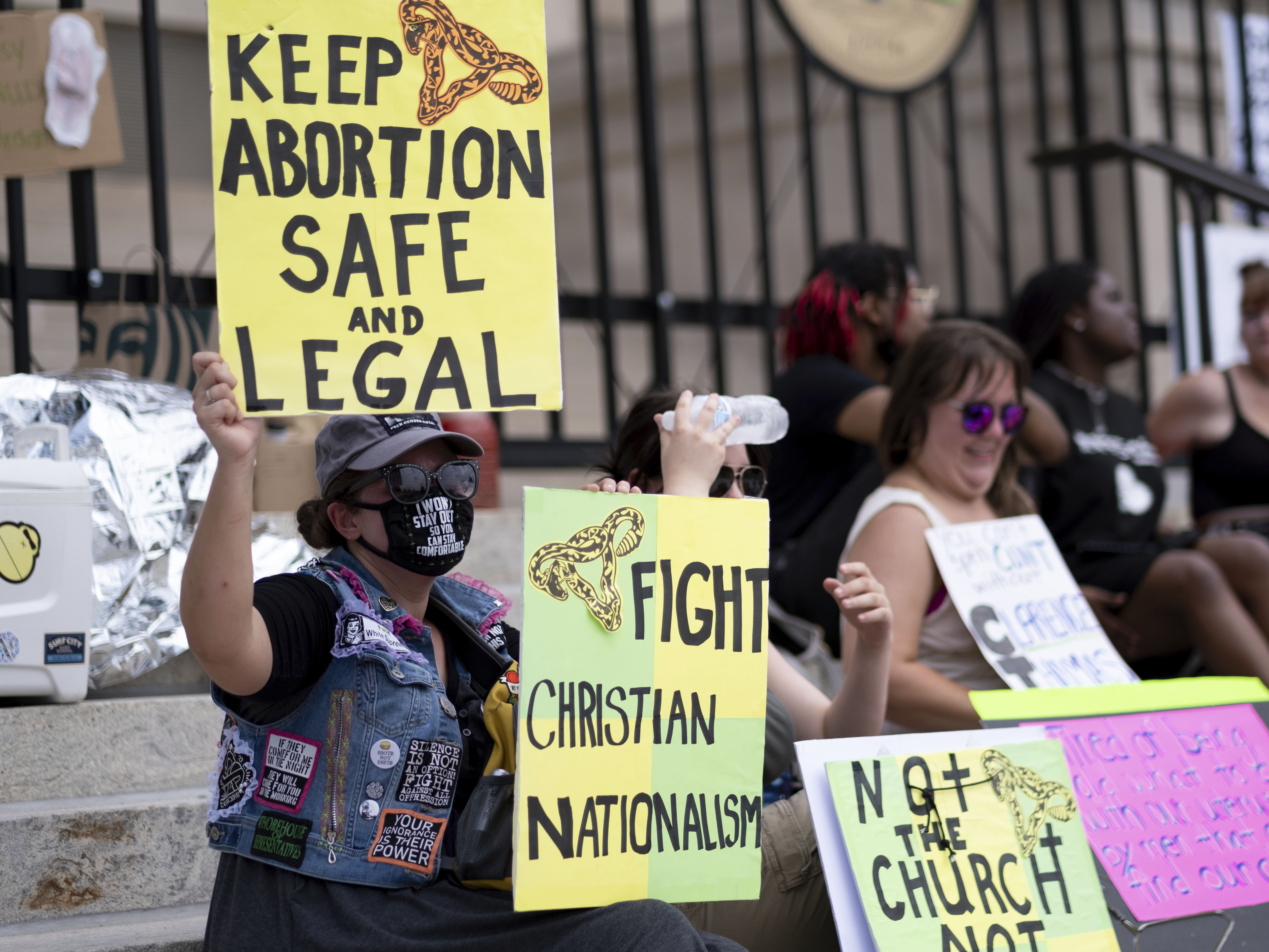 caption: A small group, including Stephanie Batchelor, left, sits on the steps of the Georgia state Capitol protesting the overturning of Roe v. Wade on June 26, 2022. The Georgia Supreme Court on Wednesday, Nov. 23, reinstated the state's ban on abortions after roughly six weeks of pregnancy.