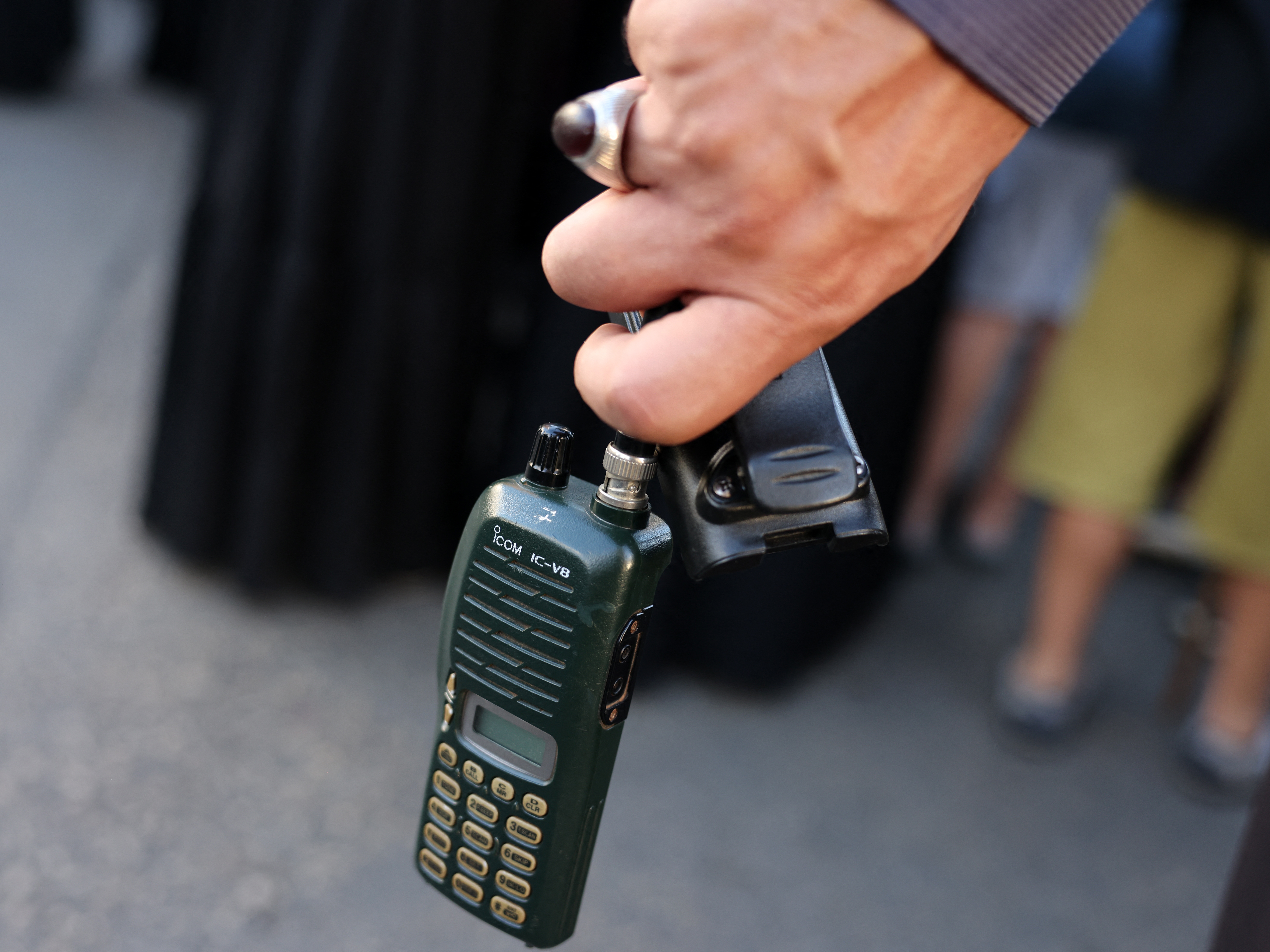 caption: A man holds an Icom walkie-talkie after he removed the battery during a funeral of people killed when hundreds of paging devices exploded in a deadly wave across Lebanon the previous day, in Beirut's southern suburbs on Sept. 18.